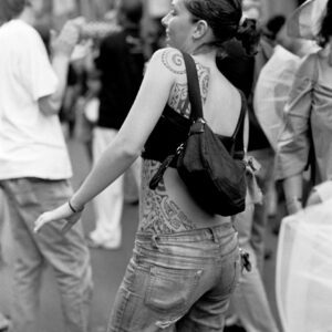 Black and white photograph of a woman with tribal tattoos dancing in the crowd during the Par tòt Parata street parade in Bologna, Italy, on June 9, 2007.