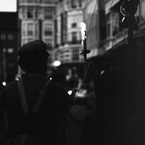 Black and white silhouette of a participant with a lit torch mechanism against the backdrop of Brussels architecture during the Joyeuse Entrée of the Zinneke Parade on May 21, 2010.